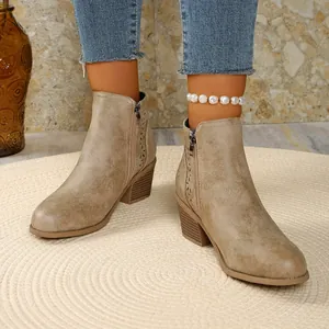 Gedetailleerd zicht op kaki Chelsea boots met blokhak en lasergesneden bloemmotieven