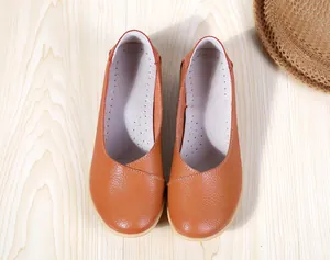 Top view detail of orange leather women's flat loafers on wooden surface