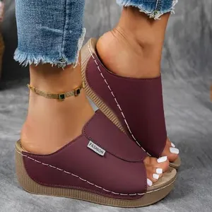 Detailansicht von weinroten Keilsandalen mit weißen Nähten und einem Modelabel