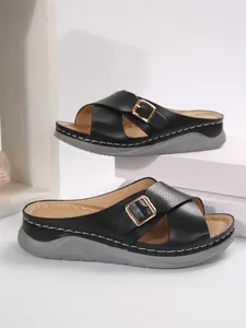 Detailed close-up view of black cross-strap sandals with gold buckles and grey soles