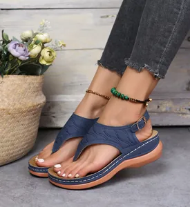 Nahaufnahme von blauen bestickten Zehentrenner-Sandalen mit Keilabsatz und Details