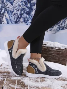 Detail of women's grey winter boots with faux fur lining in a snowy setting