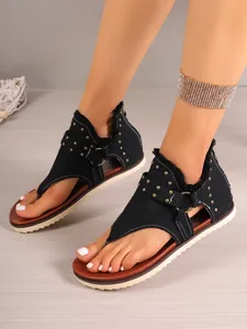 Women's black gladiator thong sandals featuring gold studs and a back zipper closure