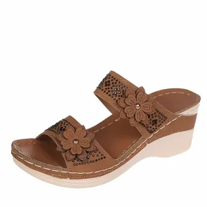 Close-up of brown floral wedge sandals with decorative black studs and white stitching