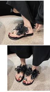 Elegante schwarze flache Sandalen mit großer Netzschleife und funkelndem Strass-Zehenring