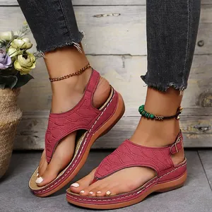Detail von weinroten Damen-Zehensandalen mit eleganter Stickerei und Keilsohle.