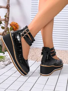 Détail d'escarpins compensés en cuir verni noir avec texture croco et brides