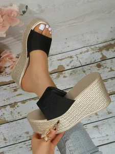 Vue détaillée de sandales compensées noires avec une semelle plateforme dorée chic.