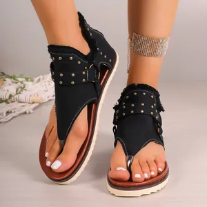 Stylish women's black flat thong sandals featuring gold studs and bohemian fringe details