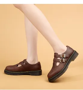 Dettaglio di scarpe Mary Jane in pelle marrone con doppia fibbia e cuciture gialle