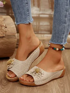 Detailed view of women's beige wedge sandals featuring flower decor and laser-cut design.