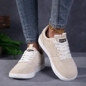 Détail de baskets décontractées crème à bout large portées avec un jean en denim bleu