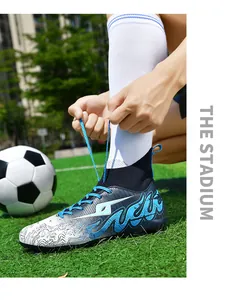 High-top soccer shoes with blue wave pattern being laced on a green turf field