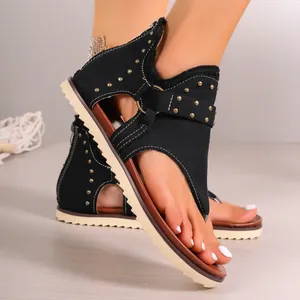 Detailed view of black thong sandals with gold studs and convenient back zipper design.