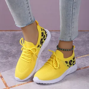 Detail view of yellow mesh sneakers with leopard print being worn by a model
