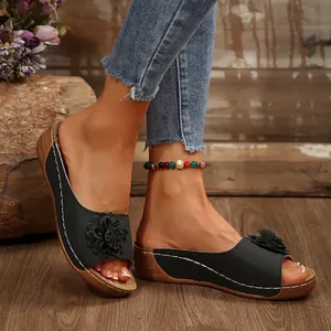 Close-up detail of stylish black wedge sandals with flower ornament and open toe design