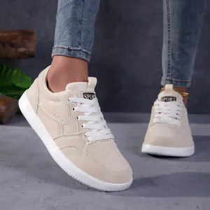 Vue rapprochée de baskets de skate rétro beige avec bout large et jean en denim bleu
