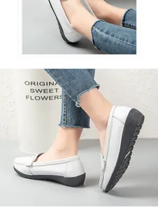Detail view of white flat leather loafers with anti-slip soles worn with denim.
