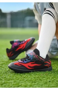 Close-up of breathable mesh children's soccer shoes with flame pattern on turf