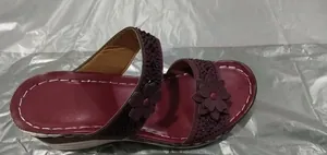 Close-up detail showing the rhinestone flower pattern on a maroon wedge sandal shoe