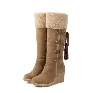 Vista lateral de botas de nieve camel con cuña, ribete de piel sintética y borla