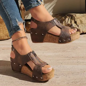 Detail shot of brown wedge sandals with front zipper, metal rivets and cork platform