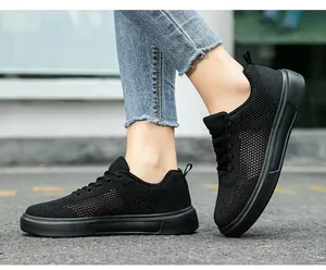 Close-up view of black breathable fly-knit sneakers on foot showing mesh texture detail