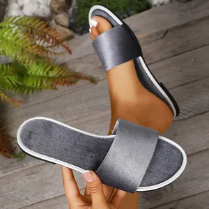 Detailed view of grey satin flat slide sandals showing material texture and on-foot fit