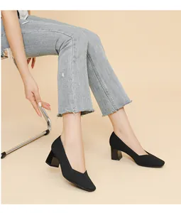 Close-up of stylish black ribbed knit block heel pumps worn with frayed denim.