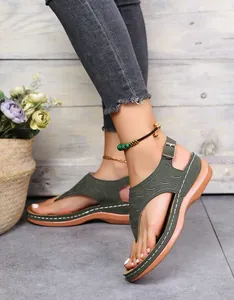 Nahaufnahme der grünen bestickten Zehentrenner-Sandalen mit Keilabsatz und Riemen