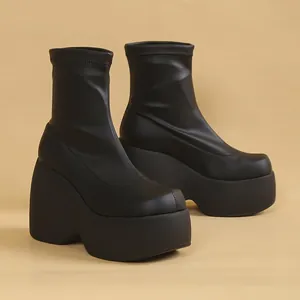 Black platform wedge ankle boots with thick sole and stretchy material in a minimalist style