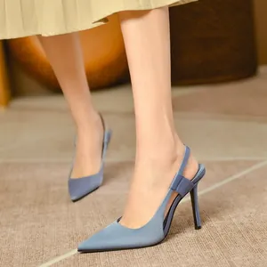 Elegant blue satin pointed-toe slingback stiletto heels worn by a model with a pleated skirt.
