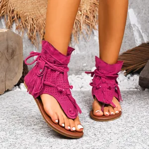 Primer plano de sandalias planas fucsia de ante con flecos y detalles perforados