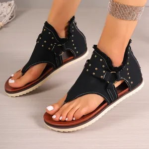 Detailed view of black denim thong sandals featuring gold studs and a back zipper closure.
