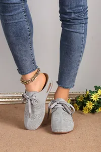 Detailed close-up of grey lace-up perforated clog sandals with stylish wedge heels.