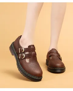 Primo piano di scarpe Mary Jane in pelle marrone con doppia fibbia e cucitura gialla.