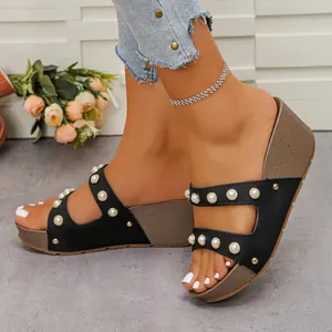 Gros plan de sandales à talons compensés pour femmes avec perles et rivets dorés.