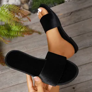 Close-up of elegant black satin slide sandals for women featuring a flat indoor/outdoor sole.