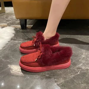 Gros plan de mocassins d'hiver rouges en fourrure avec nœud sur le pied d'un modèle.