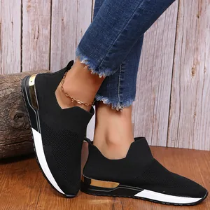 Gros plan sur des baskets noires en tricot respirant avec détails dorés.