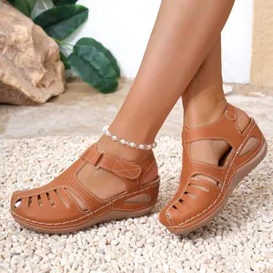 Close-up view of brown Roman wedge sandals with white stitching and hollow-out detail.