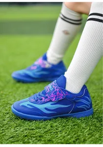 Detail of breathable blue mesh children's soccer shoes with turf studs on grass