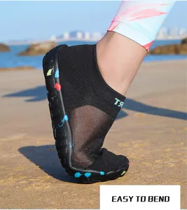Close-up of flexible black water shoes showing the easy-to-bend rubber sole on beach
