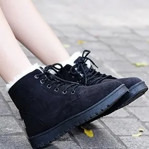 Warm black faux fur lined lace-up ankle boots for women on outdoor stone pavement