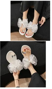 Detailansicht weißer Sandalen mit großer Tüllschleife und Strass-Zehenring.