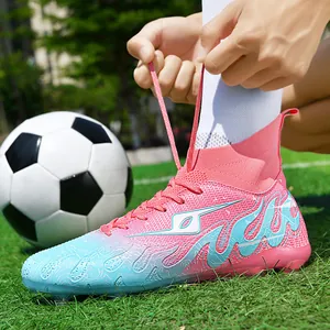 Professional high-top kids soccer cleats with pink and blue flame patterns on a grass field