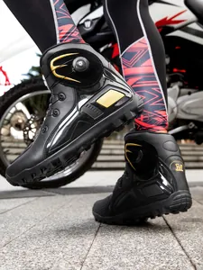 Detalle de botas de moto negras con cierre giratorio y elegantes detalles dorados.