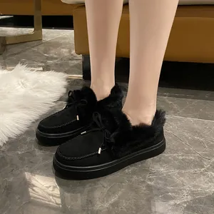 Gros plan sur des mocassins d'hiver noirs pour femmes avec bordure en fourrure et nœud