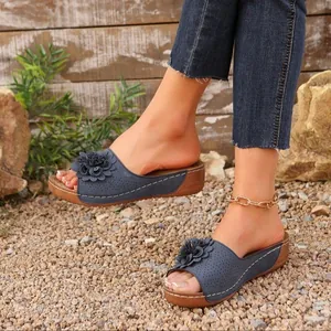 Elegant blue women's wedge sandals with decorative flower detail shown on model outdoors