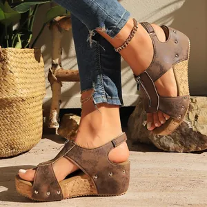 Side view of women's brown wedge sandals with rivet details and cork texture soles.